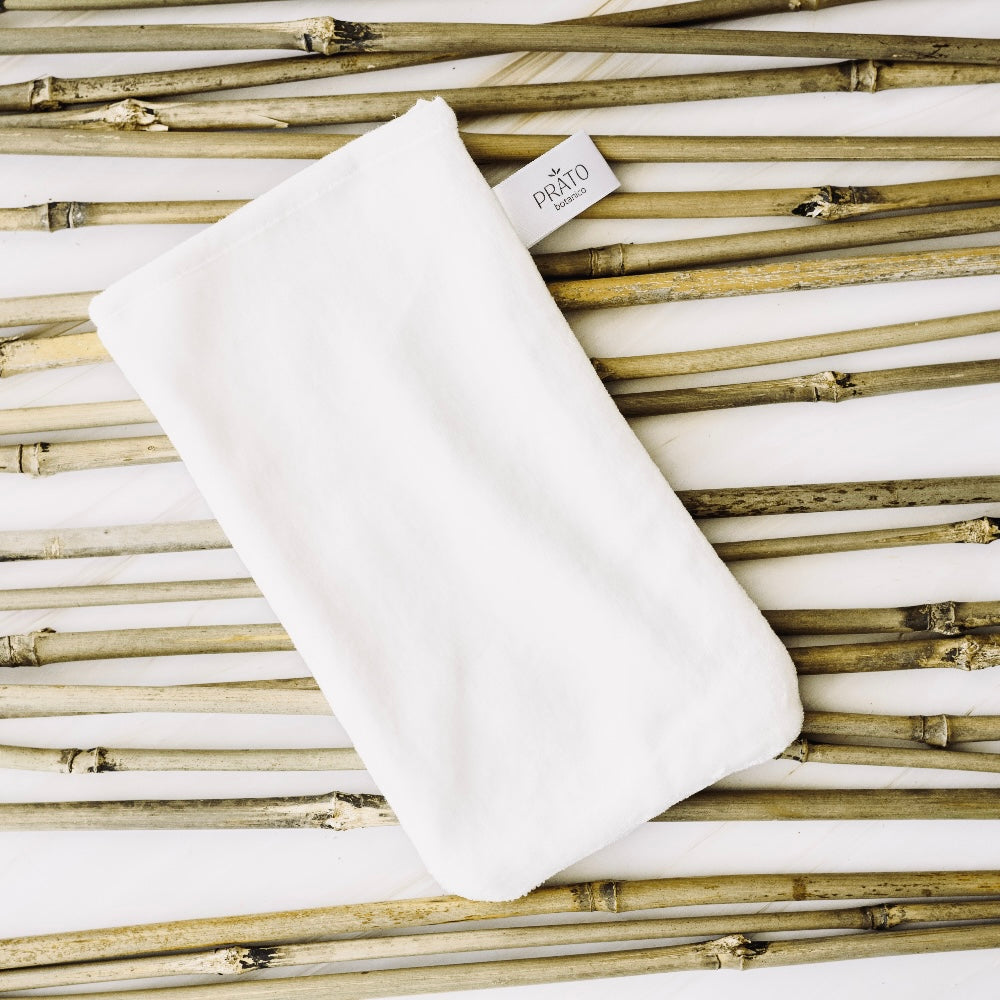 Prato Botanico Bamboo Cleansing Glove laying on bamboo shoots