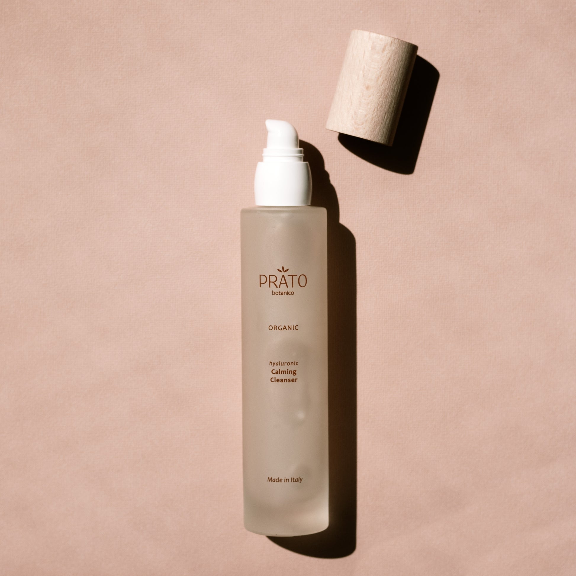 Prato Botanico Calming Cleanser on pink background next to sustainable beechwood lid